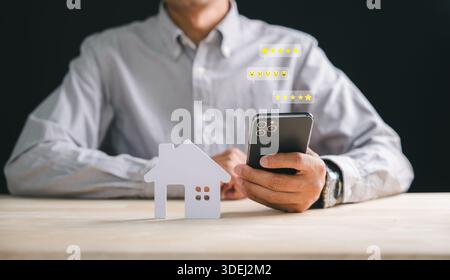 Le nouvel utilisateur de smartphone avec découpe à la maison donne des commentaires sur la propriété, montrant l'évaluation des clients immobiliers via le système d'examen d'application mobile, service en ligne pour acheter Banque D'Images