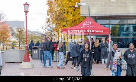Les étudiants se rassemblent sous la tente uOttawa pendant l'événement sur le campus, mettant en valeur le feuillage automnal vibrant et l'atmosphère animée de la vie universitaire à Ottawa Banque D'Images