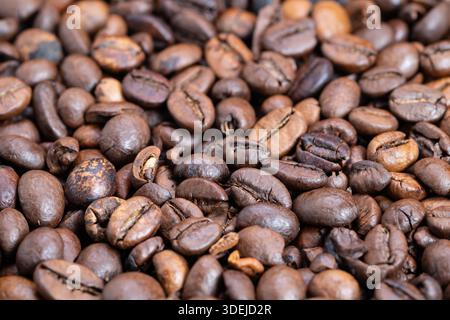 Grains de café torréfiés à poils larges dans le contexte de la production en vrac, tas uniforme et couverture dense suggèrent l'approvisionnement en gros, l'échelle des marchandises et la R industrielle Banque D'Images