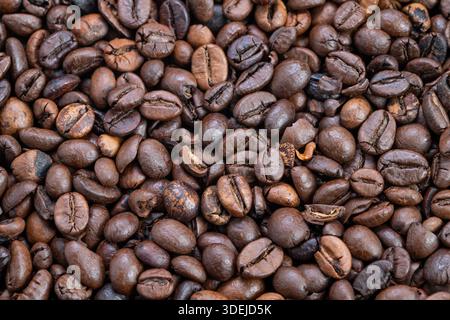 Close-up dark espresso coffee beans with oily sheen and deep brown color, tight composition emphasizing intensity and bold flavor profile for cafe and Banque D'Images