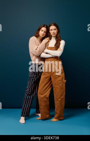 Les sœurs jumelles embrassent, rayonnant de chaleur et de joie dans un cadre confortable. Banque D'Images