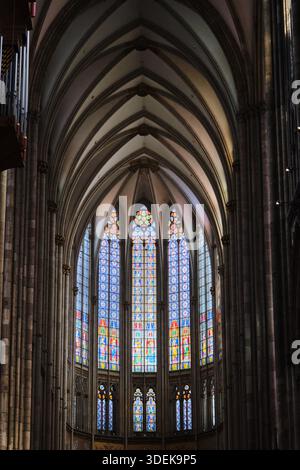 Vue captivante à l'intérieur d'une grande cathédrale gothique, mettant en évidence son majestueux plafond voûté et un vitrail complexe. Banque D'Images