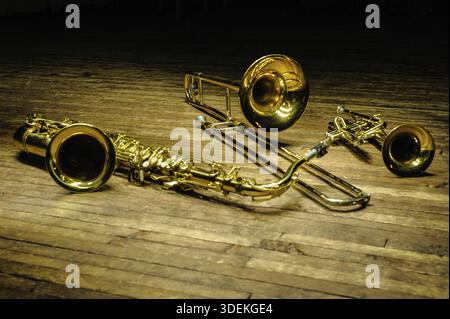 Instruments jaunes en laiton et vent - saxophone, trombone, trompette sur une scène en bois avec rétroéclairage Banque D'Images