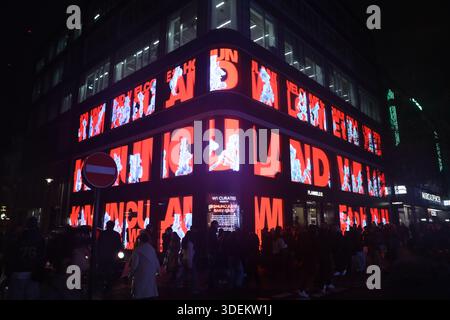 Vue nocturne d'un bâtiment sur Oxford Street, Londres, exposant une gigantesque installation d'art numérique pendant les célébrations de Noël de décembre 2025. Banque D'Images