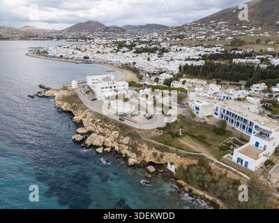 Vue aérienne des bâtiments blanchis à la chaux contrastant avec les eaux turquoises, nichés sur la côte rocheuse sous un ciel nuageux, Paros, Paros, Gr Banque D'Images