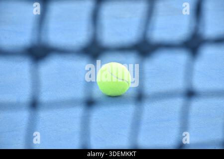 terrain jaune de chute de balle de tennis à travers le filet sur le sol bleu Banque D'Images