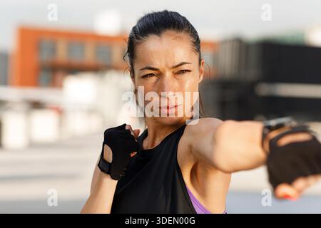 Portrait en plein air très détaillé d'une femme forte dans des gants pratiquant la boxe d'ombre || modèle libéré Banque D'Images