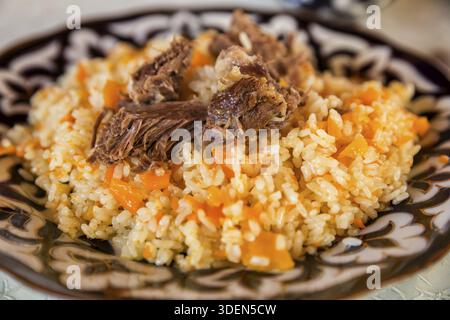 Uzbek pilaf, a traditional dish of Central Asian cuisine, on a plate with oriental pattern Banque D'Images