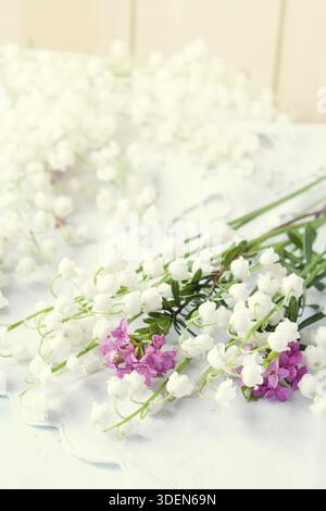 Lis blanc de la vallée sur une table en bois clair. Coloriage et traitement de photos dans un style vintage avec une mise au point sélective douce. Belle fleur de printemps b Banque D'Images