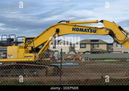 Une grande excavatrice travaille sur un chantier de construction dans un quartier. Les maisons voisines peuvent être vues en arrière-plan. Banque D'Images