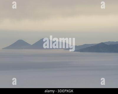 Vue aérienne des îles enveloppées de brume, leurs sommets perçant à travers le voile éthéré, une scène tranquille de la grandeur de la nature, îles éoliennes, Messi Banque D'Images