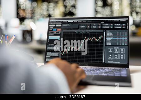 Analyste masculin noir surveillant et documentant les tendances du marché mondial, étudiant les données forex au bureau en dehors des heures de bureau. Application des connaissances financières et de l'analyse économique pour la croissance organisationnelle. Banque D'Images
