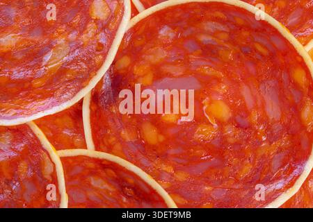 morceaux de chorizo macro avec des gouttelettes de fromage et d'huile, texture poreuse visible, couleur rouge vif, arôme salé implicite, parfait pour les tapas, planches à collation, et Banque D'Images