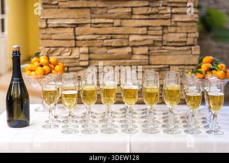 Bouteille de champagne et rangée de flûtes remplies prêtes pour un toast. Banque D'Images