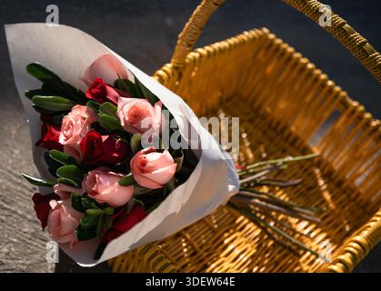 bouquet de roses dans un panier en osier jaune à l'extérieur Banque D'Images