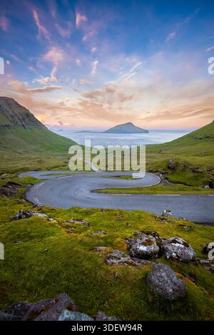 Vue d'une route sinueuse menant à l'île de Koltur en arrière-plan. Streymoy, Torshavnar district, Îles Féroé, Danemark, Scandinavie. Banque D'Images