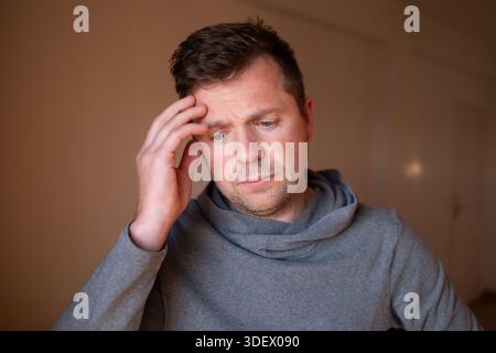 Mâle stressé ayant un terrible mal de tête ou une douleur migraine, touchant la tempe. Photo de haute qualité Banque D'Images