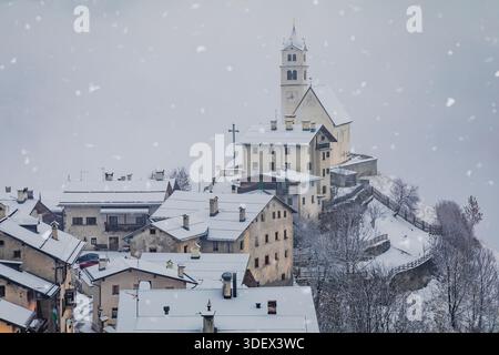 Village alpin de colle Santa Lucia avec son église historique et ses maisons en hiver sous la neige qui tombe, Dolomites, province de Belluno, Vénétie, Italie Banque D'Images