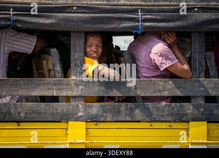 Garçon malgache sourit de la fenêtre ouverte d'un taxi-brousse, Toliara, Madagascar. Les taxis-brousses restent la méthode la plus économique et la plus populaire pour les voyages longue distance, reliant Toliara à des villages reculés et à des grandes villes comme Antananarivo. Banque D'Images