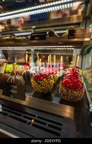 Un affichage vibrant de pommes bonbons sur des bâtons, avec des revêtements de caramel rouge brillant, des gouttes de chocolat, et des noix croquantes ou des revêtements de saupoudrés dans un sho Banque D'Images