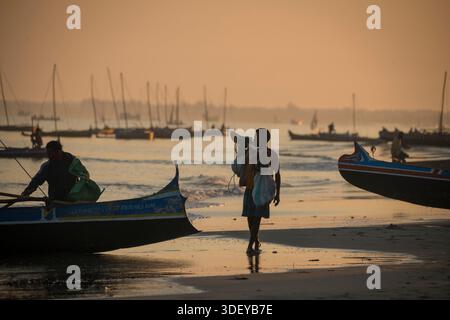 Homme malgache debout sur la plage, silhouetté contre la lumière de l'aube qui se rassemble. Partez pêcher dans un canoë-kayak, connu localement sous le nom de piroque, dans la lumière du petit matin. La pêche à Morombe, une ville côtière du sud-ouest de Madagascar, est une partie essentielle de l'économie et de la culture locales, principalement motivée par les méthodes artisanales et traditionnelles utilisées par le peuple Vezo, qui sont des pêcheurs traditionnels et se considèrent comme les propriétaires de la mer. Morombe, Madagascar. Banque D'Images
