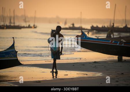 Homme malgache debout sur la plage, silhouetté contre la lumière de l'aube qui se rassemble. Partez pêcher dans un canoë-kayak, connu localement sous le nom de piroque, dans la lumière du petit matin. La pêche à Morombe, une ville côtière du sud-ouest de Madagascar, est une partie essentielle de l'économie et de la culture locales, principalement motivée par les méthodes artisanales et traditionnelles utilisées par le peuple Vezo, qui sont des pêcheurs traditionnels et se considèrent comme les propriétaires de la mer. Morombe, Madagascar. Banque D'Images
