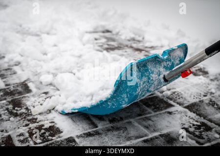 Sturmtief Elli bringt dem Norden Schnee und Glätte Oldenburg, Deutschland, 09.2026, Detailaufnahme einer Schneeschaufel, mit der frischer Schnee von einem gepflasterten Gehweg geräumt wird. Seit dem frühen Morgen schneit und stürmt es, weiterer Schneefall wird bis in die späten Abendstunden erwartet. *** La tempête Elli apporte de la neige et de la glace au nord Oldenburg, Allemagne, 09 01 2026 gros plan d'une pelle à neige utilisée pour déneiger un trottoir pavé. Elle neige et prend de l'assaut depuis tôt le matin, et d'autres chutes de neige sont attendues jusque tard dans la soirée Banque D'Images