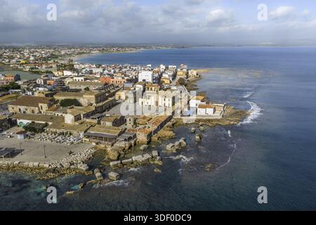 Vue aérienne des bâtiments ensoleillés et de la Piazza Regina Margherita rencontrant la mer turquoise, Marzamemi, Sicile, Italie. Banque D'Images