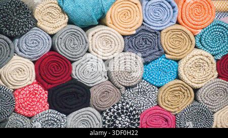 Tissus roulés de différentes couleurs, motifs et textures disposés ensemble, mettant en valeur la diversité textile et le savoir-faire artisanal. Banque D'Images