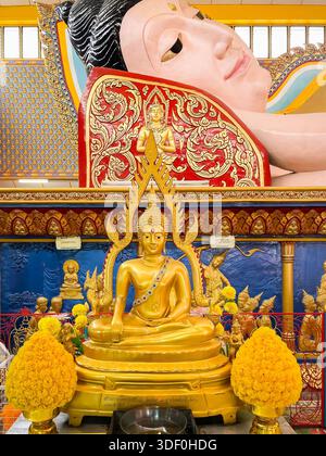 Statue de Bouddha doré avec des détails complexes devant le grand Bouddha couché à l'intérieur du temple Wat Chayamangkalaram décoré de manière vibrante à l'intérieur de penan Banque D'Images