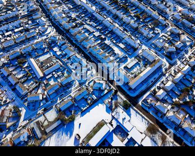 Vue de haut en bas des toits et des routes de banlieue créant un motif après les chutes de neige hivernales Banque D'Images