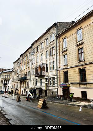 Lviv, Ukraine - 29 novembre 2025 : rénovation d'une rue urbaine sur un ancien bâtiment avec des ouvriers et des barrières de sécurité le long du trottoir à Lviv, Ukraine. Banque D'Images