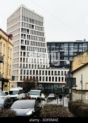 Lviv, Ukraine - 29 novembre 2025 : paysage urbain avec un grand bâtiment blanc moderne, rue animée et piétons par une journée nuageuse à Lviv, Ukraine. Banque D'Images