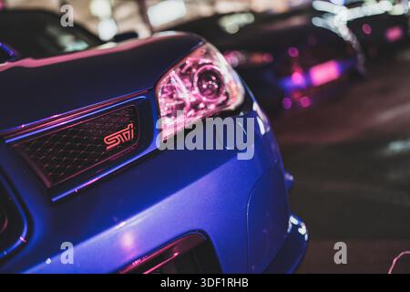 Rome, italie 9 janvier 2025 : gros plan avant subaru wrx sti avec phares et calandre violet et rose néon, ambiance de réglage jdm dans la lumière de nuit urbaine Banque D'Images
