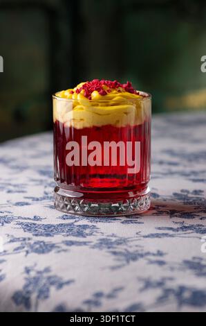 Cocktail rouge avec mousse jaune et poudre de framboise. Banque D'Images