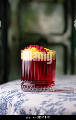 Cocktail rouge avec mousse jaune et poudre de framboise. Banque D'Images