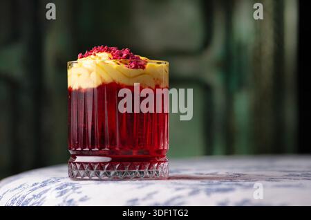 Cocktail rouge avec mousse jaune et poudre de framboise. Banque D'Images