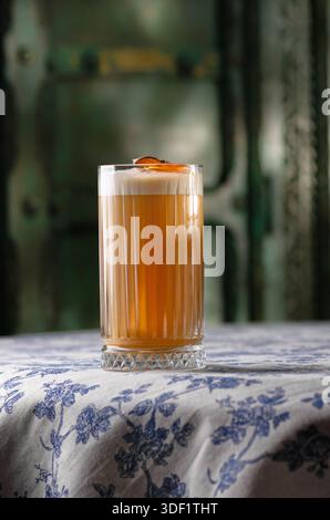 Rafraîchissant cocktail Sweet Pumpkin, boisson savoureuse d'alcool dans un verre, mur sur le fond. Le cocktail est sur une table. Banque D'Images
