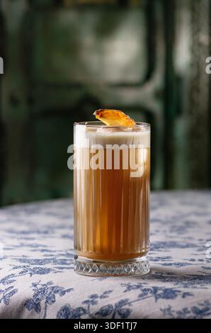 Rafraîchissant cocktail Sweet Pumpkin, boisson savoureuse d'alcool dans un verre, mur sur le fond. Le cocktail est sur une table. Banque D'Images