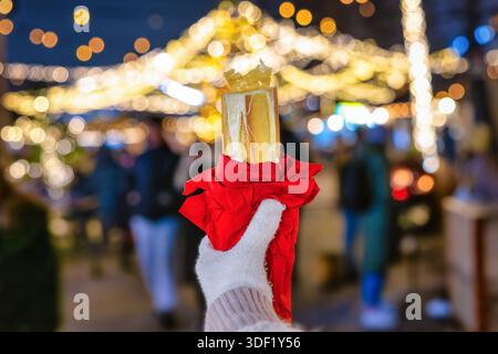 Une main tenant une baguette à fondue au fromage chaud sur un marché de Noël en Suisse comme spécialité locale Banque D'Images