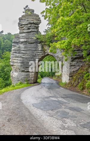 Arc rocheux en grès encadrant une route sinueuse entourée d'une forêt verdoyante en Tchéquie Banque D'Images