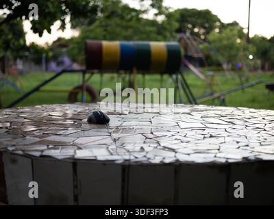 Souris d'ordinateur sur une table de mosaïque dans un parc, suggérant un espace de travail portable et l'utilisation de la technologie extérieure. Banque D'Images