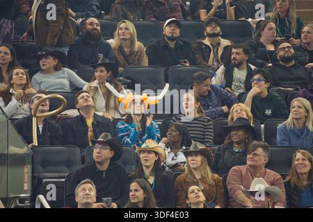 Une foule diversifiée de spectateurs, dont beaucoup portent des chapeaux, sont assis dans une arène intérieure, regardant vers le haut. Banque D'Images