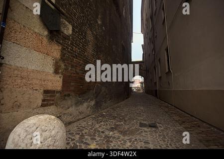 Étroite ruelle pavée, partiellement à l'ombre, avec un passage au-dessus Banque D'Images