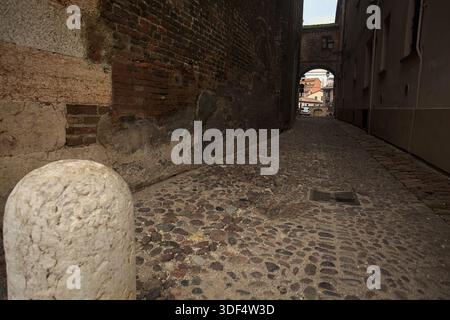 Étroite ruelle pavée, partiellement à l'ombre, avec un passage au-dessus Banque D'Images
