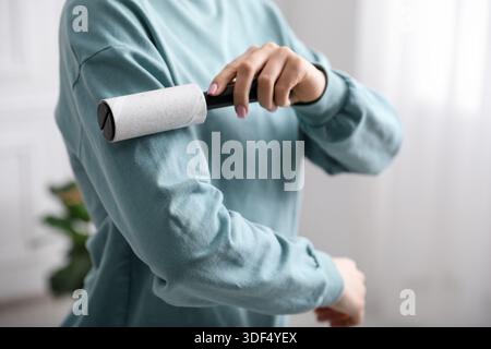 Femme nettoyant sweat-shirt avec rouleau à peluches à la maison, gros plan Banque D'Images