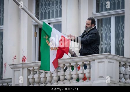 Londres, Royaume-Uni. 10 janvier 2026. Un membre du personnel de l’ambassade iranienne se prépare à retirer le drapeau monarchiste Lion et Soleil après qu’un manifestant ait déchiré et remplacé le drapeau iranien de l’ambassade de la République islamique d’Iran au milieu d’affrontements avec la police alors que des démos contre le régime de l’ayatollah se sont répandues dans le monde entier. Des milliers de manifestants se sont rassemblés devant l’ambassade samedi en scandant « rendez l’Iran grandiose ». La police a confirmé deux arrestations pour désordre. Crédit : Guy Corbishley/Alamy Live News Banque D'Images