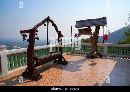 Banc en bois rustique traditionnel et cloches suspendues au temple Wat Phra That Doi Kham sur le flanc de la montagne de Chiang mai, dans le nord de la Thaïlande Banque D'Images