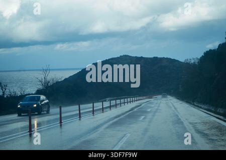 Photo spectaculaire de l'autoroute BOAK en Crète reliant Héraklion et Rethymno.Wet asphalte reflète le ciel orageux sur la mer Méditerranée près de Panormo Banque D'Images
