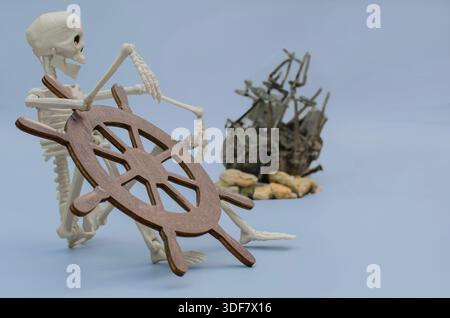 Une nature morte conceptuelle mettant en scène un squelette humain modèle tenant une barre en bois avec un naufrage flou en arrière-plan, des histoires de fantômes et un voy perdu Banque D'Images